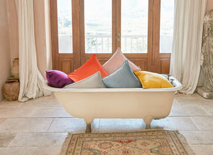Velvet cushions and matte velvet curtains in a bathtub in a vintage marble bathroom with a claw foot bathtub